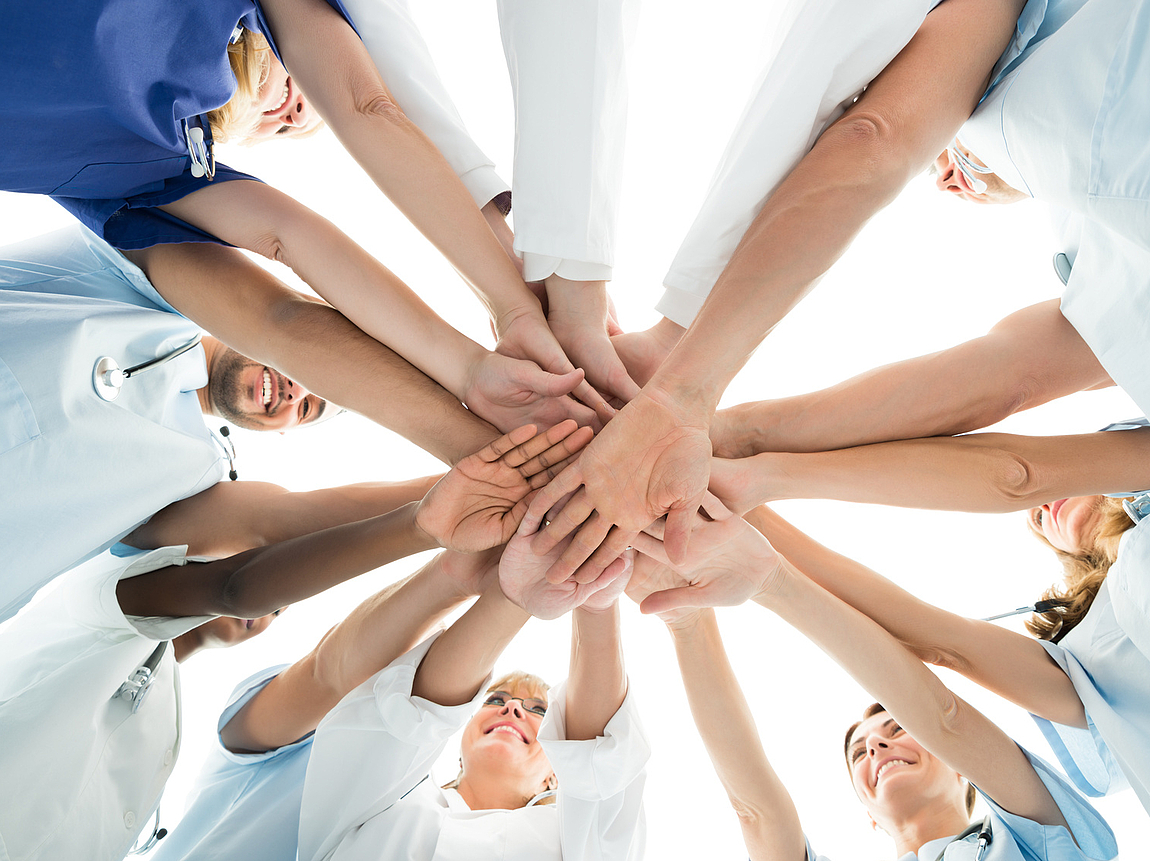 Im Team Hand in Hand Team steht im Kreis und legt Hände in der Mitte aufeinander